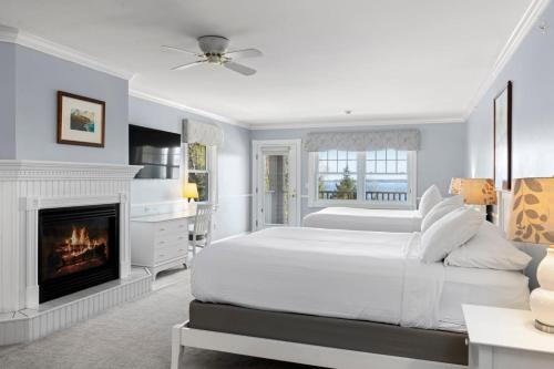 a white bedroom with a fireplace and a bed at The Inn at Ocean's Edge in Lincolnville