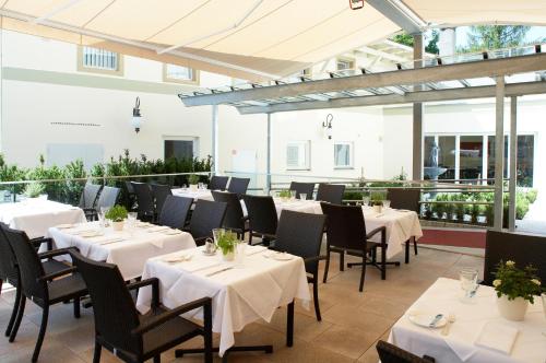 um restaurante com mesas e cadeiras brancas e janelas em Hotel Weißes Kreuz em Bregenz