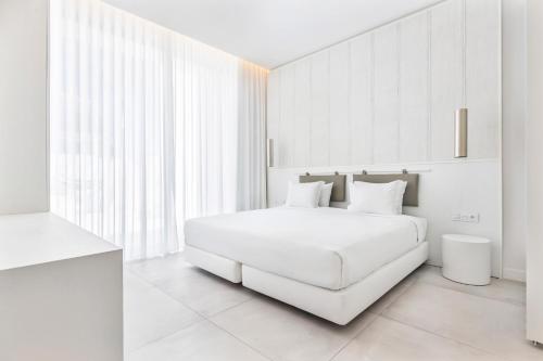 a white bedroom with a white bed and a window at Vila Maria Hotel - Adults Only in Albufeira