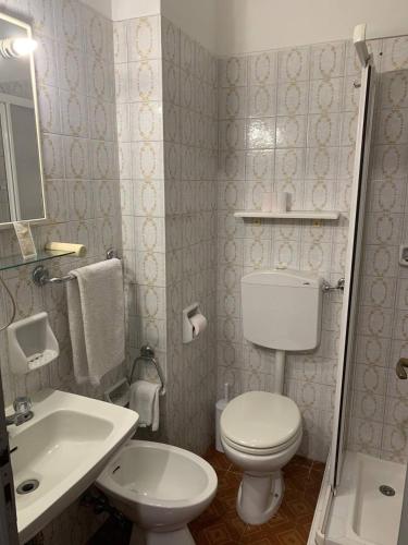 a white bathroom with a toilet and a sink at Amica in Salsomaggiore Terme