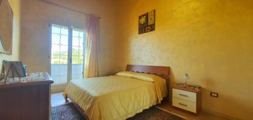 a yellow bedroom with a bed and a window at Cristian Apartaments in Capo Vaticano