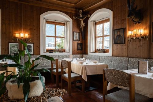 a dining room with tables and chairs and windows at Hotel Senningerbräu in Bramberg am Wildkogel