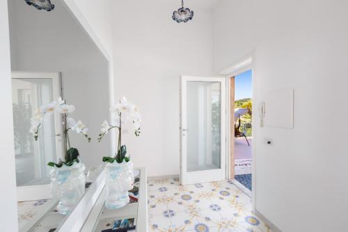a white room with flowers in vases on a table at Villa Fedora Sea&Stars in Massa Lubrense