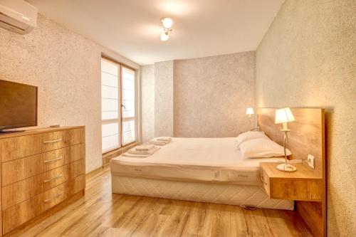 a bedroom with a large bed and a television at Complex Hunter's Beach in Shkorpilovtsi