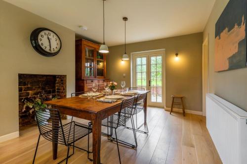 a dining room with a table and a clock on the wall at Haclins Cottage - Norfolk Holiday Properties in Fakenham