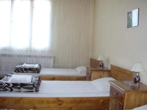 a room with three beds and two tables and a window at Family Hotel "May" in Petrich