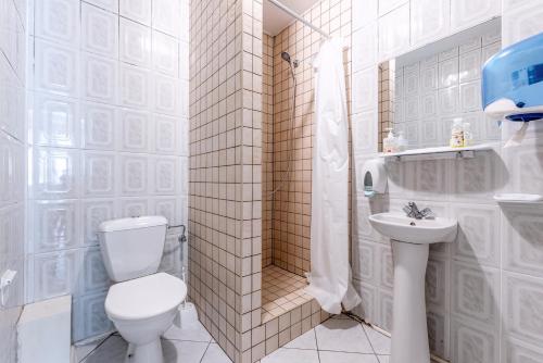 a white bathroom with a toilet and a sink at Vila Jelita in Nida