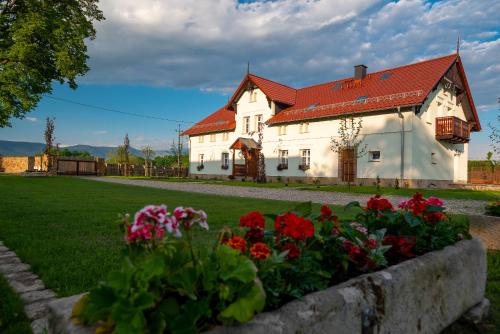 a white house with a red roof and flowers at Dworek Wojanów in Wojanów