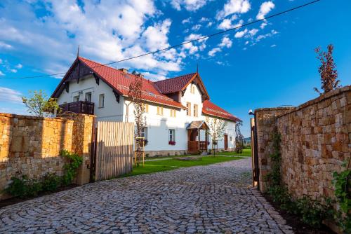a white house with a red roof and a brick fence at Dworek Wojanów in Wojanów