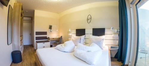 a bedroom with a white bed with white pillows at Pension Julia & Haus Elisabeth - Wallner's Hofheuriger & Weinhof in Mörbisch am See