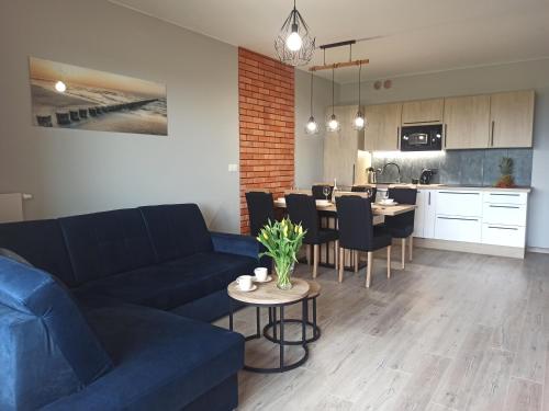 salon z kanapą i stołem z krzesłami w obiekcie Apartament z basenem i klimatyzacją w Sarbinowie