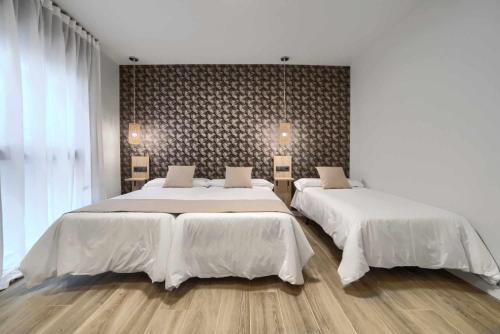 una camera da letto con due letti con lenzuola bianche di Apartamento rural Isla Esencia de Bardenas Navarra a Villafranca