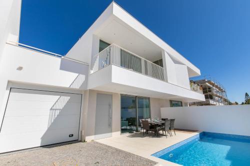 a white house with a swimming pool and a table at Casa Branca 40 in Lagos