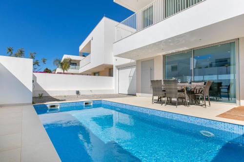 a house with a swimming pool and a dining table at Casa Branca 40 in Lagos
