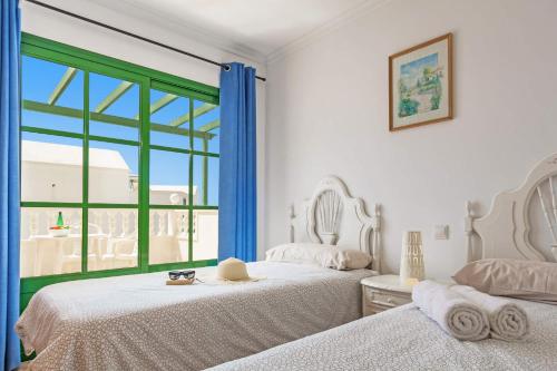 a white bedroom with two beds and a window at Villa Plata by Villa Plus in Puerto del Carmen