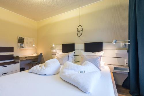 a bedroom with a bed with white pillows and a desk at Pension Julia & Haus Elisabeth - Wallner's Hofheuriger & Weinhof in Mörbisch am See