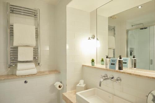 a white bathroom with a sink and a mirror at The Georgian, Haslemere, Surrey in Haslemere