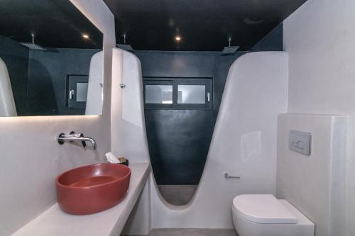 a bathroom with a red sink and a toilet at Sunset junior suites in Agios Ioannis Tinos