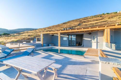 a villa with a pool and a table and chairs at Sunset junior suites in Agios Ioannis Tinos
