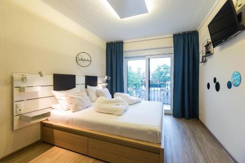 a bedroom with a large white bed with a window at Pension Julia & Haus Elisabeth - Wallner's Hofheuriger & Weinhof in Mörbisch am See