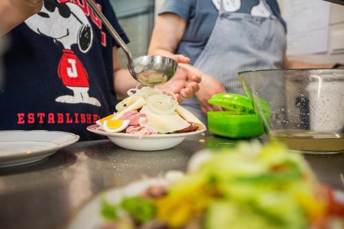 a person is making a salad with a bowl of food at Pension Julia & Haus Elisabeth - Wallner's Hofheuriger & Weinhof in Mörbisch am See