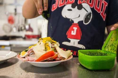 a person in a kitchen with a plate of food at Pension Julia & Haus Elisabeth - Wallner's Hofheuriger & Weinhof in Mörbisch am See