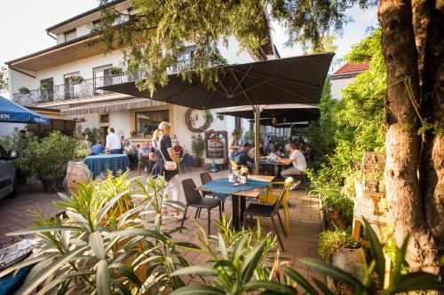 a group of people sitting at a table under an umbrella at Pension Julia & Haus Elisabeth - Wallner's Hofheuriger & Weinhof in Mörbisch am See