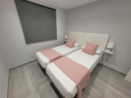 two beds in a hotel room with pink pillows at Apartamentos Bluebelle - Marbella in Marbella