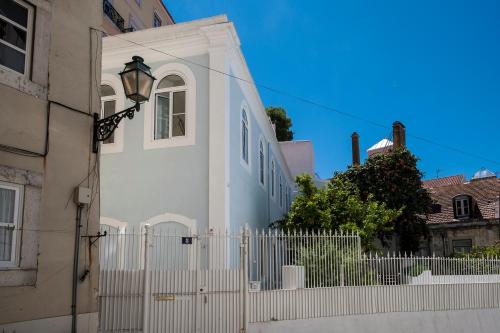 a white house with a white fence and a gate at Portas do Castelo Apartments in Lisbon
