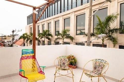Duas cadeiras sentadas num pátio em frente a um edifício em Casa 39-33 em Cartagena das Índias
