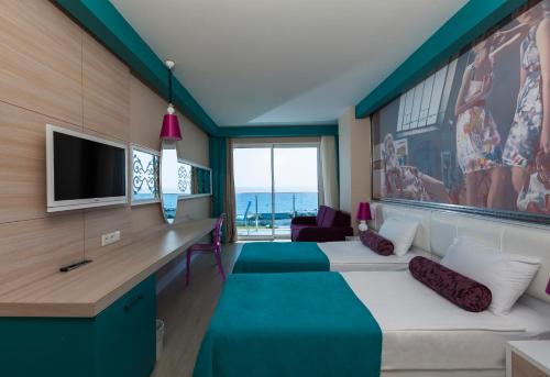 a room with two beds and a desk with a television at Sultan of Dreams Hotel & Spa in Kızılot