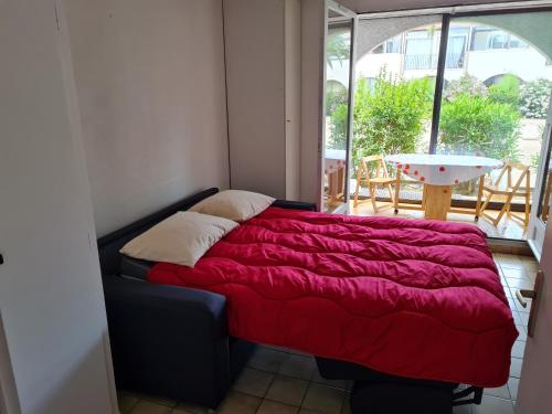 Ce lit se trouve dans un dortoir doté d'une couverture rouge. dans l'établissement L HACIENDA - appartement 4 à 5 personnes proche plage et port - Parking, à Saint-Cyprien