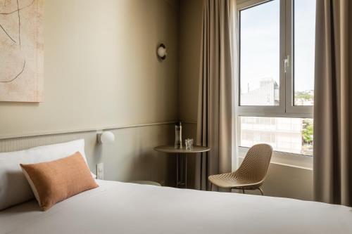 ein Schlafzimmer mit einem Bett, einem Fenster und einem Stuhl in der Unterkunft BYPILLOW The Bloom in Girona