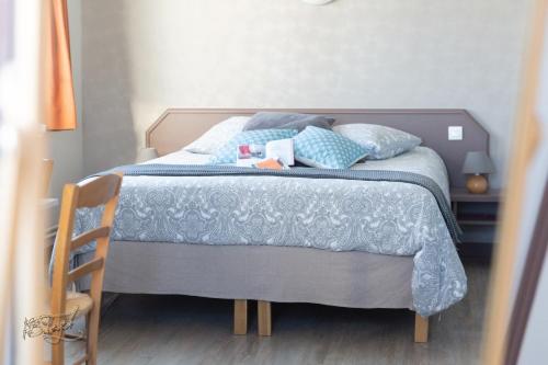a bed with a blue blanket and pillows on it at Hotel la piscine in Villers-sur-Mer