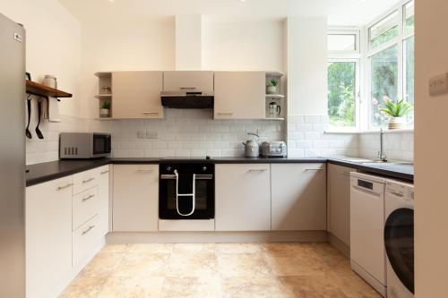 a white kitchen with white cabinets and a sink at No 5 Highwayman - Norfolk Cottage Agency in Sheringham