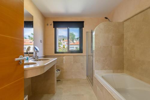 ein Badezimmer mit einer Badewanne, einem Waschbecken und einer Badewanne in der Unterkunft Tranquil 2 bed villa with private pool + sea view! in Benalmádena