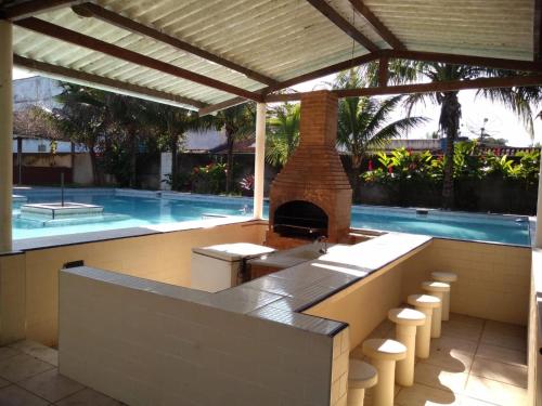 a outdoor kitchen with a fireplace next to a swimming pool at Pousada do Veleiro Azul in Angra dos Reis