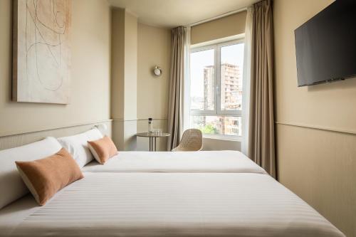 two beds in a hotel room with a window at BYPILLOW The Bloom in Girona