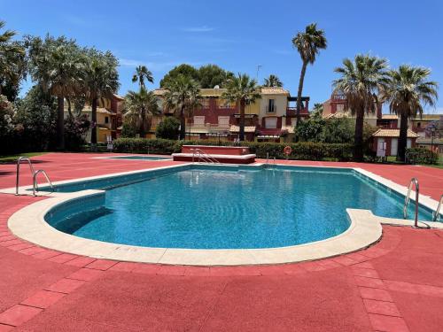 una piscina en un complejo con palmeras en A charming 6-person apartment, golf, surfing, free tennis courts and bicycles en Isla Canela