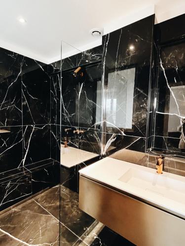 a black tiled bathroom with a sink and a mirror at Hotel San Carlu Citadelle Ajaccio in Ajaccio