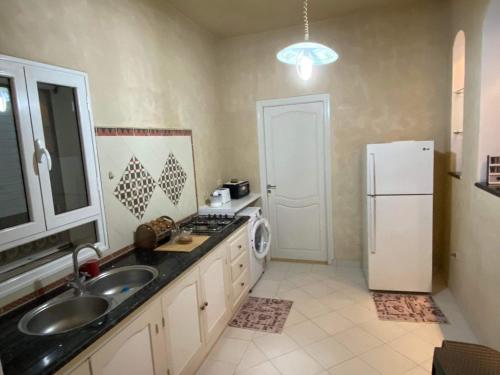 a kitchen with a sink and a white refrigerator at Villa DJERBA La Douce in Midoun