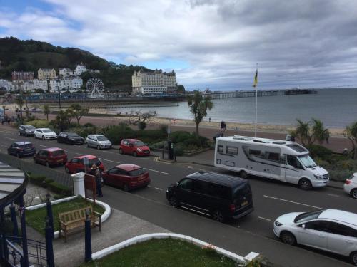 a busy city street with cars parked next to the beach at THE TREVONE, Llandudno in Llandudno
