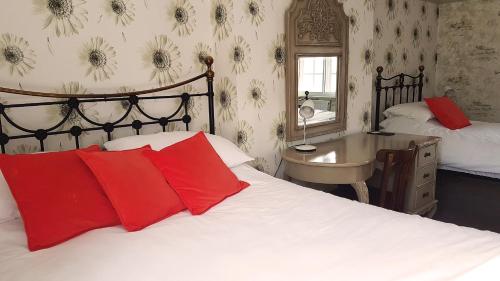 a bedroom with a bed with red pillows and a desk at The Royal Oak Duddington in Stamford