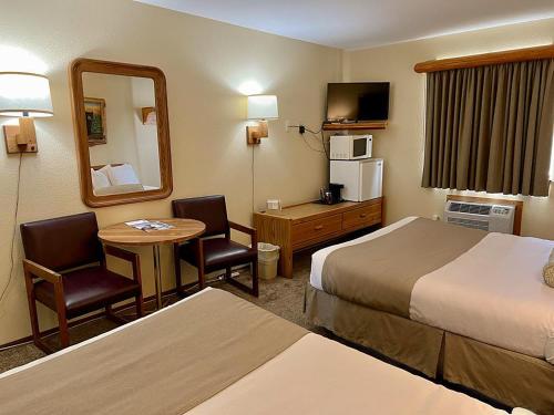 a hotel room with two beds and a table and a mirror at Beartooth Hideaway Inn & Cabins in Red Lodge
