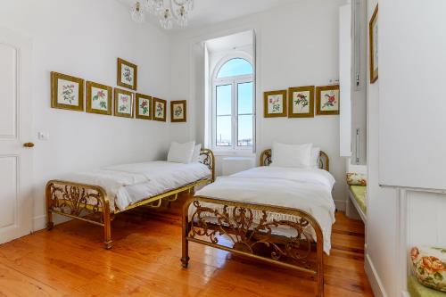 Habitación con 2 camas, paredes blancas y suelo de madera. en Portas do Castelo Apartments, en Lisboa