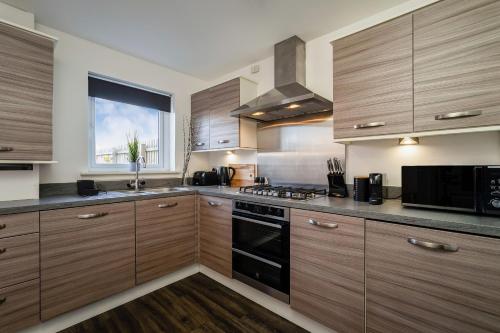a kitchen with wooden cabinets and a stove top oven at Modern 3-Bed Family Home Near Glasgow Airport in Bishopton