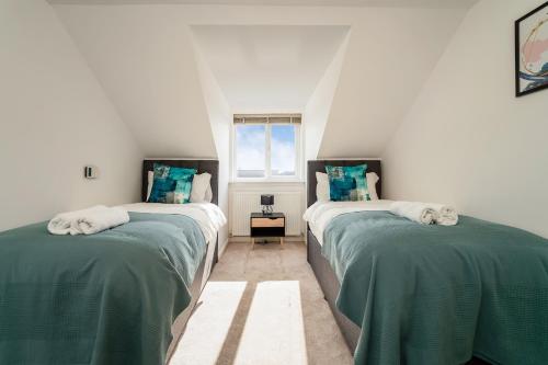 a bedroom with two beds with green sheets and a window at Anchored - Stunning Home in connected rural setting in Bishopton
