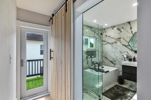 a bathroom with a glass shower and a sink at Historic Waterfront estate With Yard & Modern Kitchen in Lake Worth