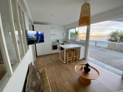 uma sala de estar com uma mesa e uma cozinha com vista em Casa Nomad - appartement cozy les pieds dans l'eau em Ploemeur