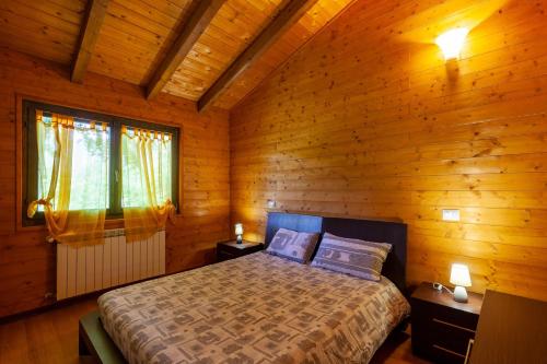 um quarto com uma cama num chalé de madeira em Villaggio Anemone Chalet Scoiattolo em Capanne di Sillano